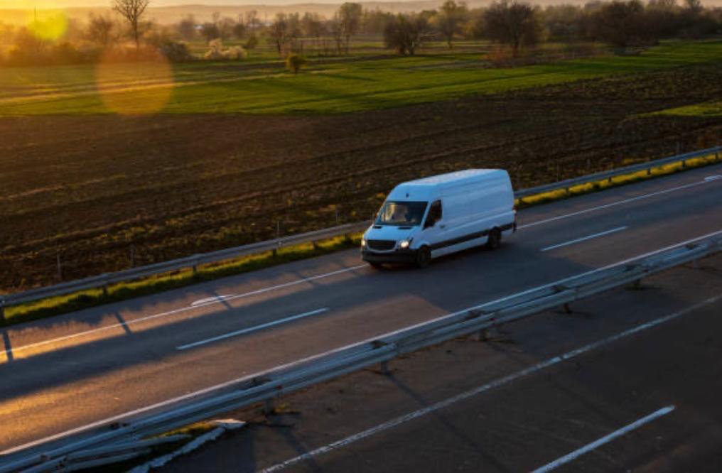 Furgoneta de reparto de GMalaga circulando por autopista con paisaje rural al fondo.